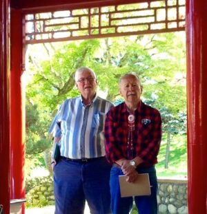 Indigenous and settler friends Hubert Barton Sr. and Doug Smart stand under an arch at a Buddhist Temple.